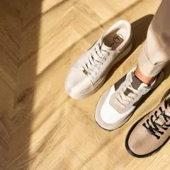 Beżowe sneakersy i półbuty na drewnianej podłodze. Idealne buty do cygaretek dla stylowej kobiety.