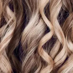 Falujące, jasne blond włosy z subtelnymi refleksami babylights, tworzącymi efekt muśnięty słońcem.
