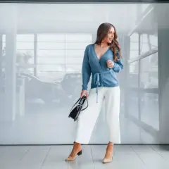 Kobieta w białych kulotach i błękitnym sweterku, zastanawia się, jakie buty do kulotów będą najlepsze. Eleganckie botki na obcasie.