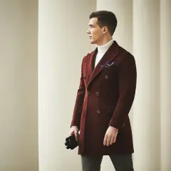 Elegancki mężczyzna w bordowej budrysówce, białym golfie i z granatową poszetką, trzymający czarne rękawiczki.