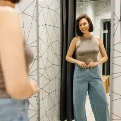 Kobieta w przymierzalni zapina jeansy. Czy w32 l32 to jej rozmiar?