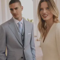 Elegancki mężczyzna w jasnym garniturze i kobieta w kremowej sukience. Inspiracja, jak się ubrać na komunię.