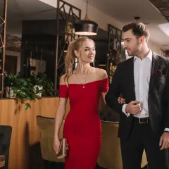 Para elegancko ubrana para, ona w czerwonej sukni, on w garniturze, idzie na wieczorne wyjście w stylu cocktail attire.