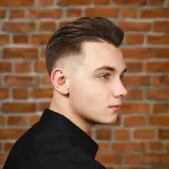 Młody mężczyzna z modną fryzurą, która dodaje mu uroku. To świetny przykład fryzury męskiej, która odmładza.
