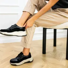 Kobieta poprawia czarne sneakersy na nogach. Dowiedz się, jak szybko wysuszyć buty, by znów cieszyć się komfortem.