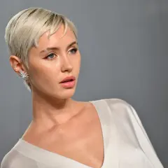 Krótkie, blond włosy i wyraziste rysy twarzy. Stylizacja z błyszczącą biżuterią, idealna jako inspiracja fryzury dla grubych twarzy.