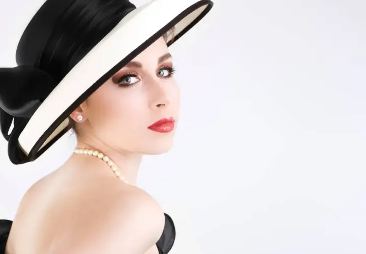 Elegancka kobieta w kapeluszu i perłach, jak z cytatów Coco Chanel. Klasa i styl.