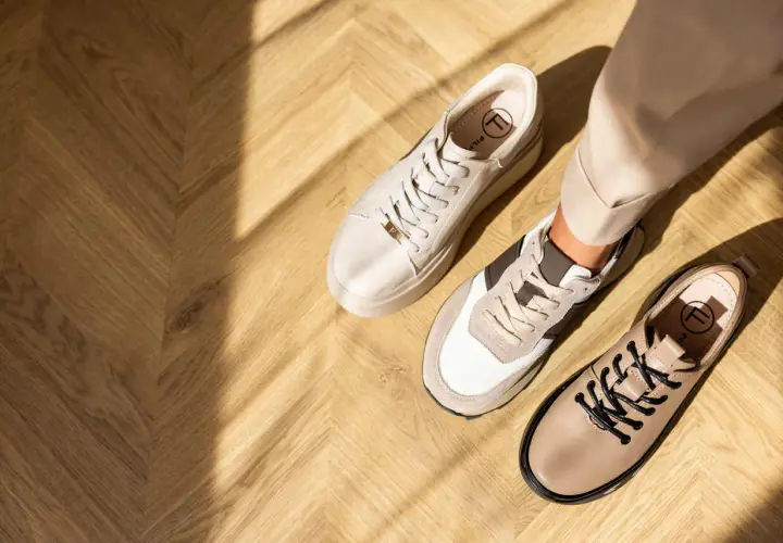 Beżowe sneakersy i półbuty na drewnianej podłodze. Idealne buty do cygaretek dla stylowej kobiety.