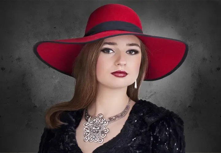 Elegancka kobieta w czerwonym kapeluszu i biżuterii, uosobienie stylu marki premium.