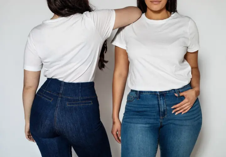 Dwie kobiety w białych T-shirtach i jeansach. Stylizacje z wysokim stanem podkreślają sylwetkę, pokazując jak ukryć brzuch.