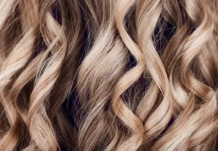 Falujące, jasne blond włosy z subtelnymi refleksami babylights, tworzącymi efekt muśnięty słońcem.
