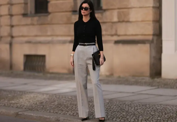 Elegancka stylizacja na imprezę dla 40-latki: czarny top, szare spodnie z wysokim stanem, czarna torebka i okulary.