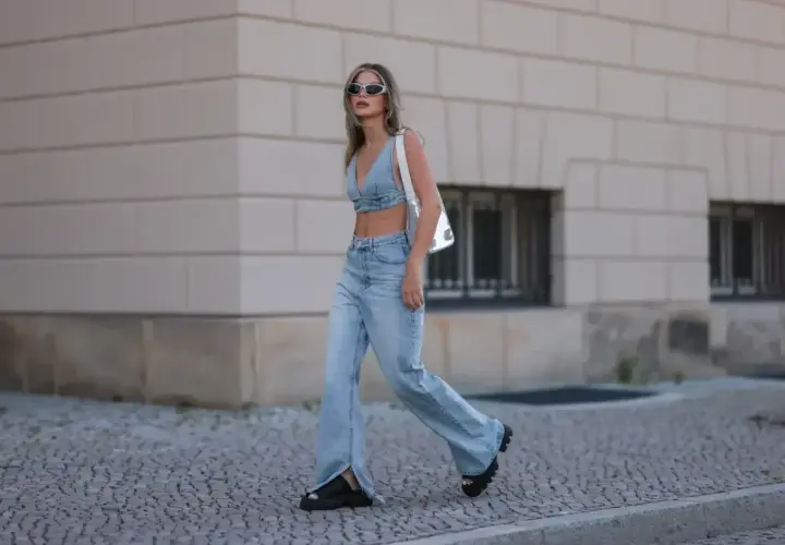 Modna kobieta w jeansach flare i denimowym topie, prezentująca letnie stylizacje.