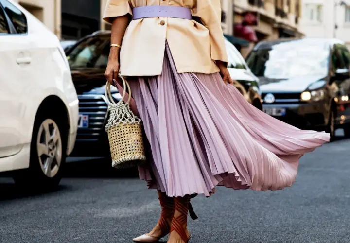 Eleganckie stylizacje z plisowaną spódnicą w pastelowym kolorze, uzupełnione wiklinową torebką i sandałami na obcasie.
