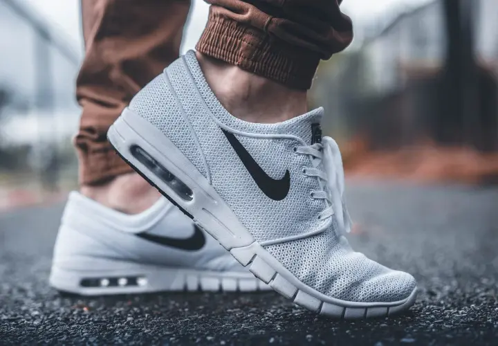 Białe buty Nike na siateczkowanej cholewce, z czarnym logo. Dowiedz się, jak wyczyścić białe buty, by wyglądały jak nowe.