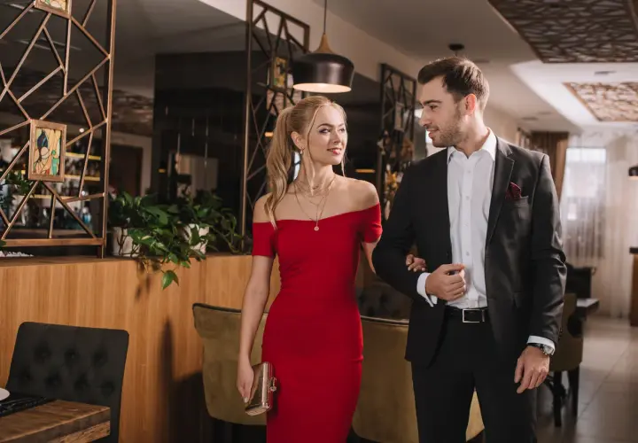Para elegancko ubrana para, ona w czerwonej sukni, on w garniturze, idzie na wieczorne wyjście w stylu cocktail attire.