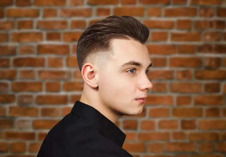 Młody mężczyzna z modną fryzurą, która dodaje mu uroku. To świetny przykład fryzury męskiej, która odmładza.