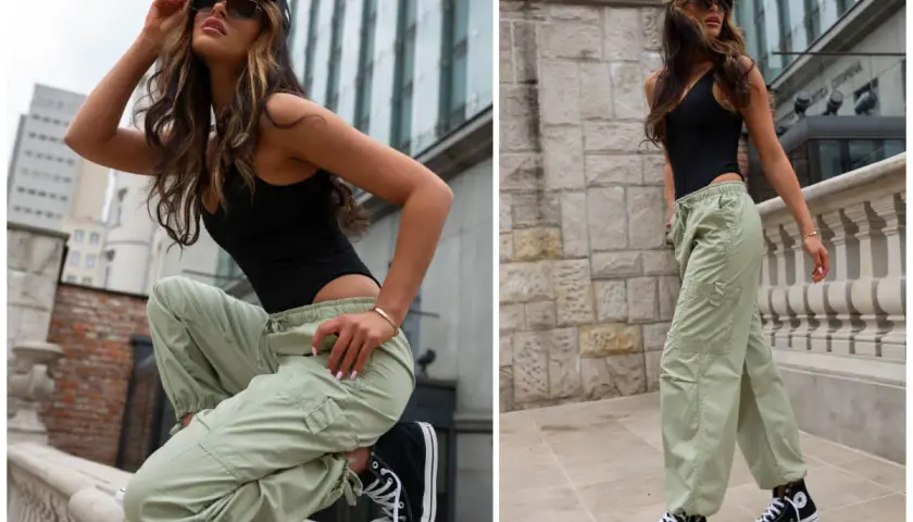 Kobieta w czarnym body i luźnych spodniach cargo w kolorze khaki, na tle miejskiej architektury.
