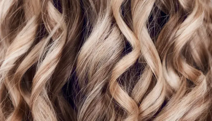 Falujące, jasne blond włosy z subtelnymi refleksami babylights, tworzącymi efekt muśnięty słońcem.