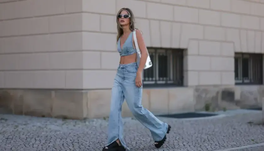 Modna kobieta w jeansach flare i denimowym topie, prezentująca letnie stylizacje.