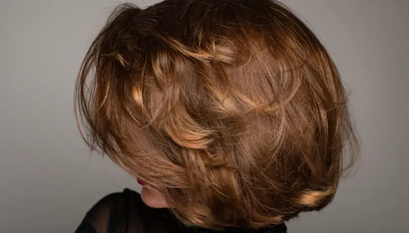 Kobieta z burzą brązowych włosów w stylu italian bob, z subtelnymi refleksami i objętością.