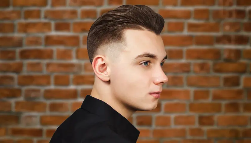 Młody mężczyzna z modną fryzurą, która dodaje mu uroku. To świetny przykład fryzury męskiej, która odmładza.