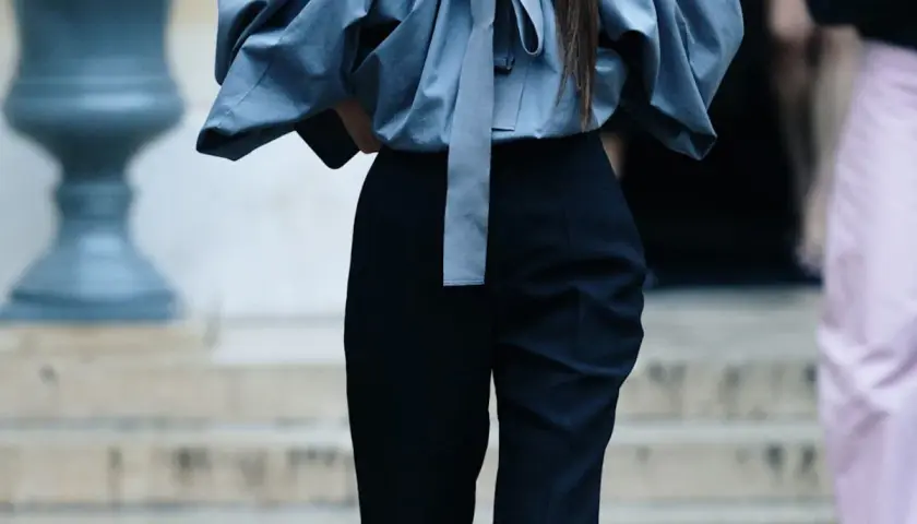 Eleganckie stylizacje z czarnymi spodniami. Szara, bufiała bluzka z kokardą i dopasowane czarne spodnie tworzą szykowny zestaw.