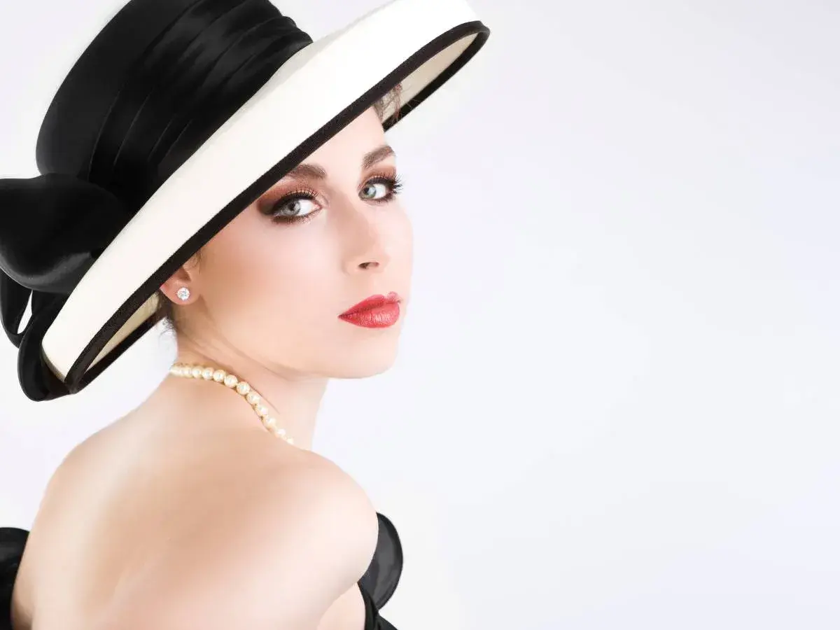 Elegancka kobieta w kapeluszu i perłach, jak z cytatów Coco Chanel. Klasa i styl.