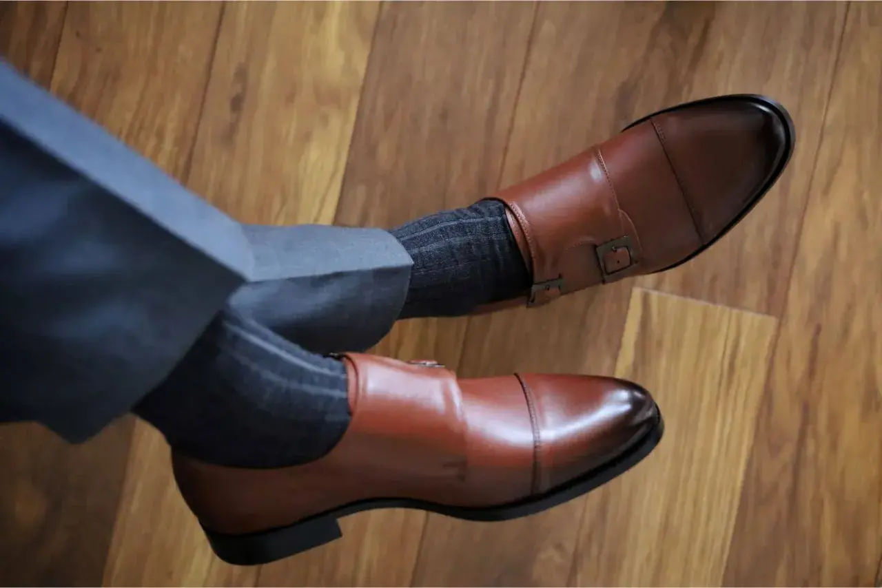 Eleganckie, brązowe buty monk strap i grafitowe skarpetki w prążki. Idealne połączenie, gdy zastanawiasz się, jakie skarpetki do brązowych butów pasują.