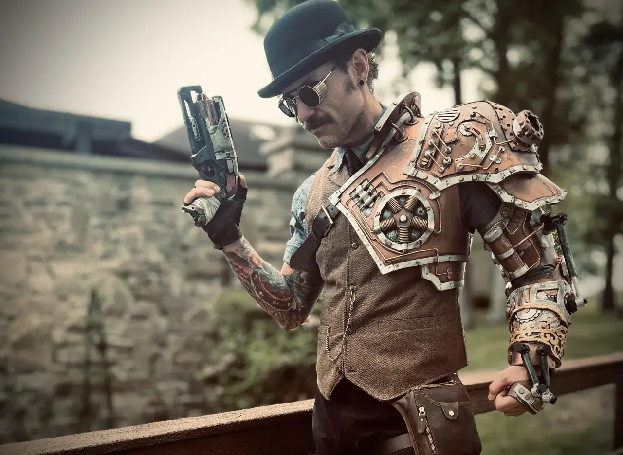 Mężczyzna w stylu steampunk, z cylindrem i goglami, trzyma futurystyczny pistolet. Jego zbroja na ramię i rękę jest pełna mechanicznych detali.