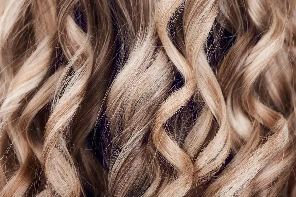Falujące, jasne blond włosy z subtelnymi refleksami babylights, tworzącymi efekt muśnięty słońcem.