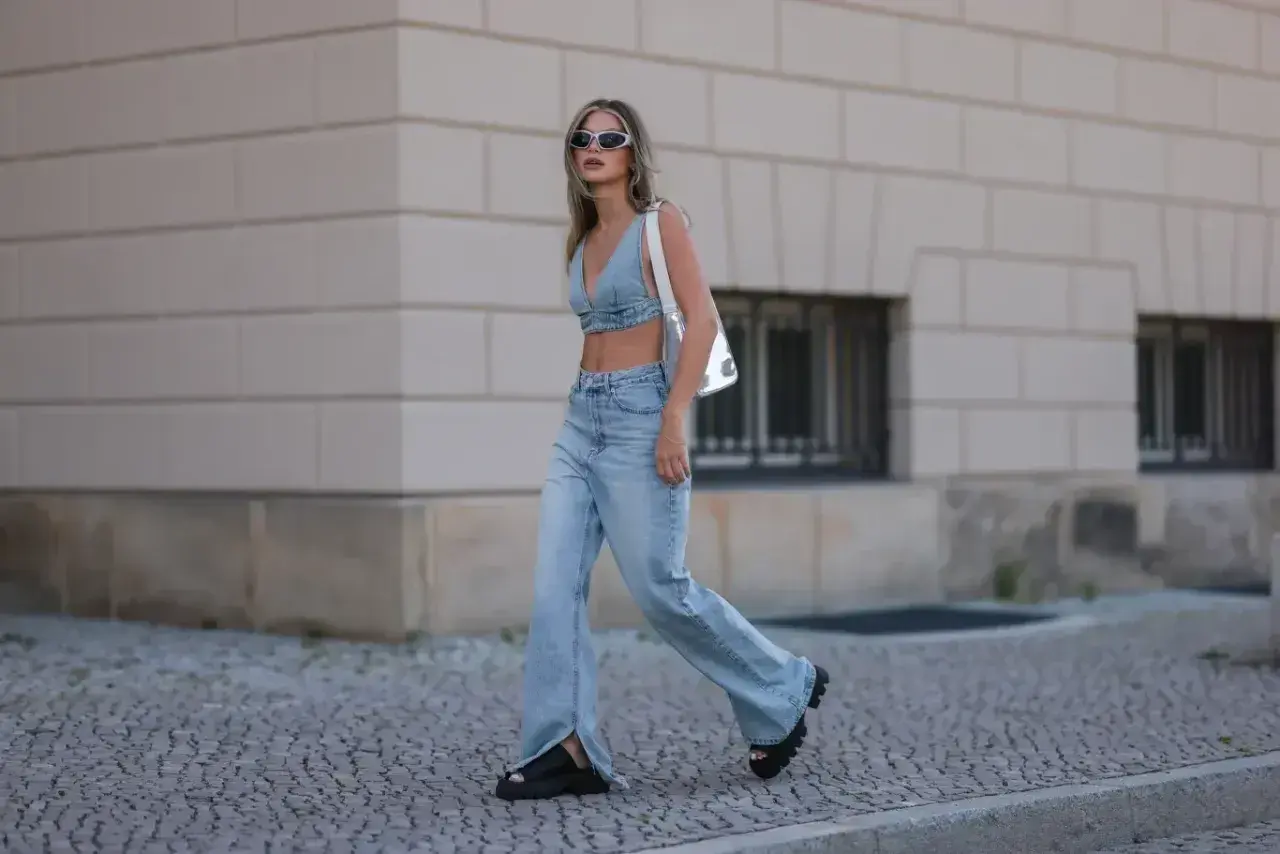Modna kobieta w jeansach flare i denimowym topie, prezentująca letnie stylizacje.