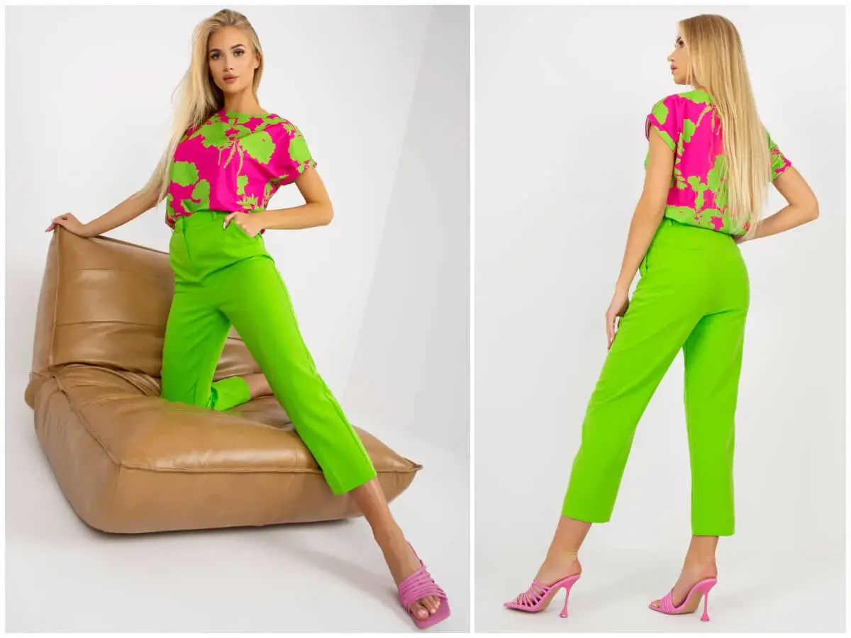 Modelka w stylizacji z bluzką w intensywny wzór i spodniami w kolorze limonkowym, siedząca na brązowej poduszce.