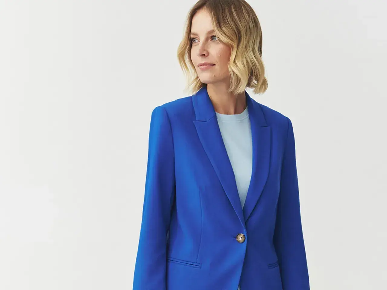 Kobieta w eleganckim, niebieskim żakiecie. Kolor kobaltowy a chabrowy idealnie podkreśla jej styl.
