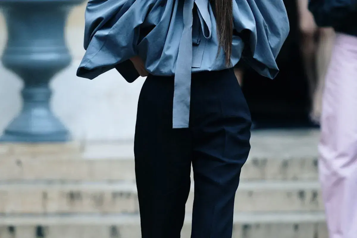 Eleganckie stylizacje z czarnymi spodniami. Szara, bufiała bluzka z kokardą i dopasowane czarne spodnie tworzą szykowny zestaw.