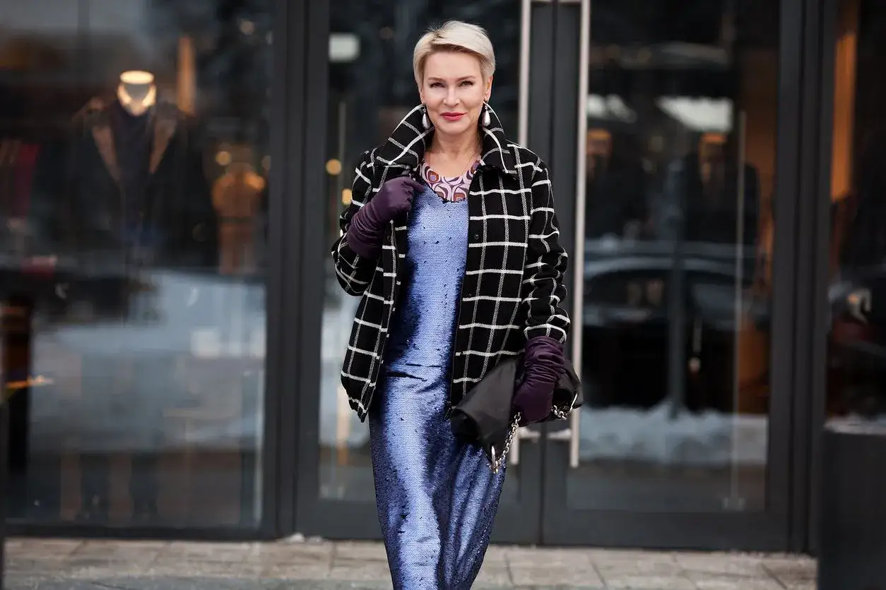 Elegancka kobieta w cekinowej sukience i rękawiczkach, niczym prawdziwa mob wife, wychodzi ze sklepu.