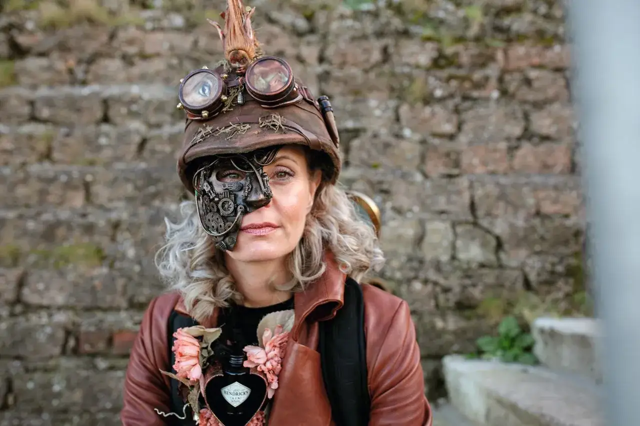 Kobieta w hełmie z goglami i mechaniczną maską na twarzy, w stylu steampunk.