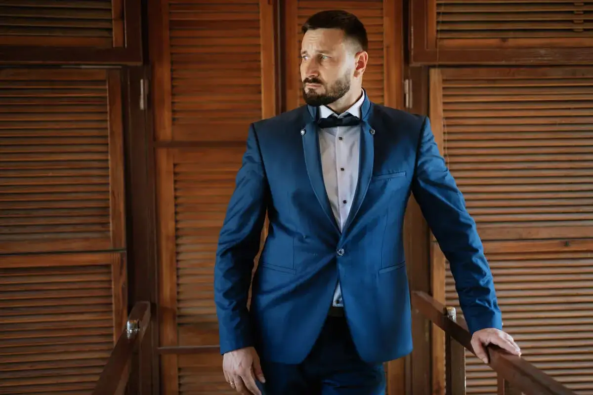 Elegancki mężczyzna w granatowym garniturze i muszce. Idealny wybór, jaki garnitur na wesele dla świadka.