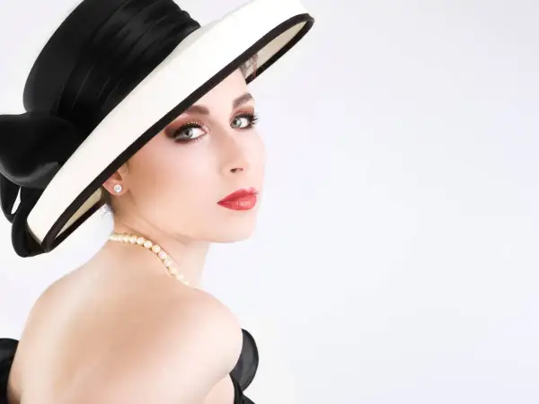 Elegancka kobieta w kapeluszu i perłach, jak z cytatów Coco Chanel. Klasa i styl.